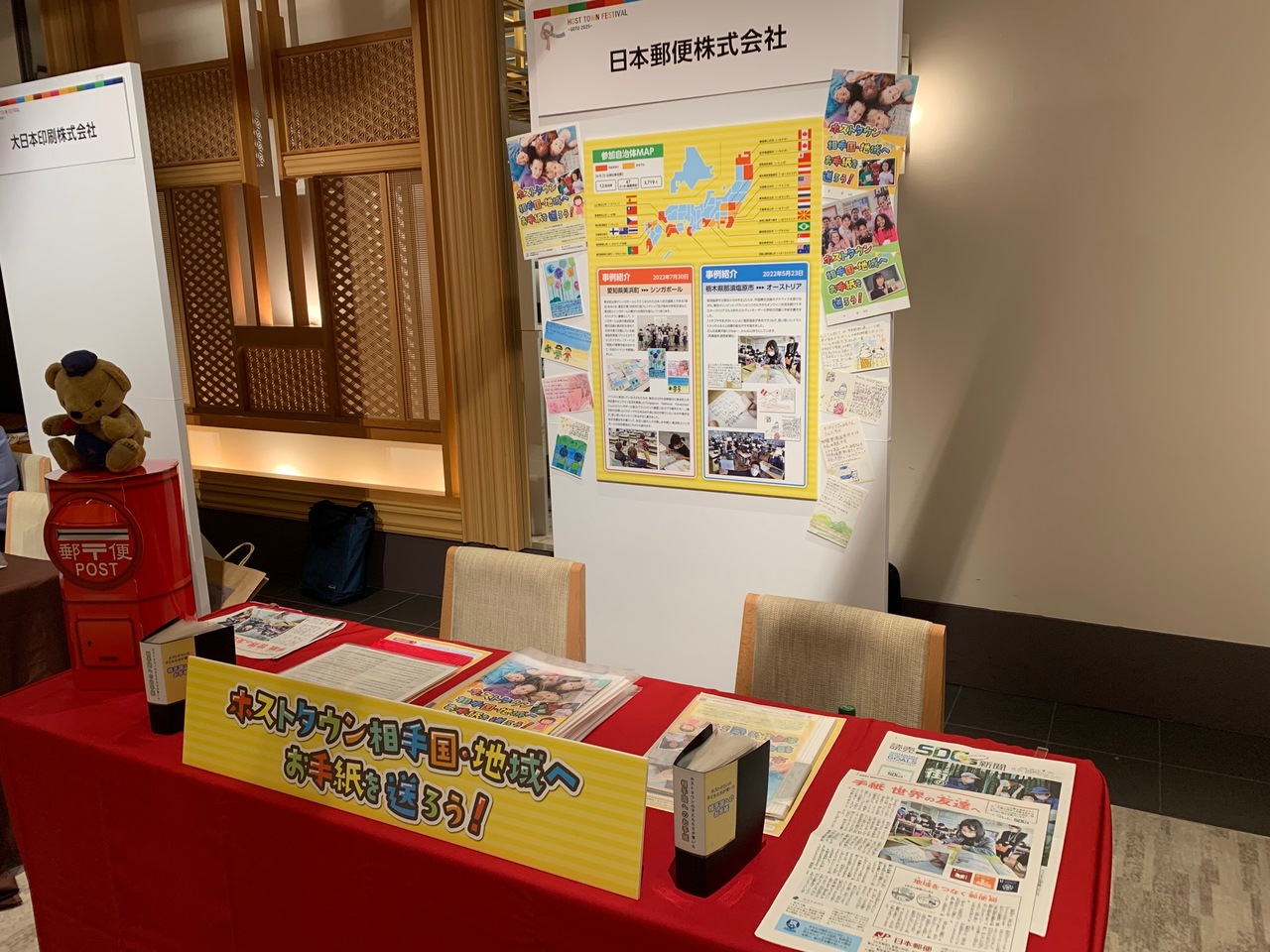 机の上に、小さなポストの上にぽすくまのぬいぐるみが置かれ「ホストタウン相手国・地域へお手紙を送ろう!」などについての解説やポスター新聞などを写した写真