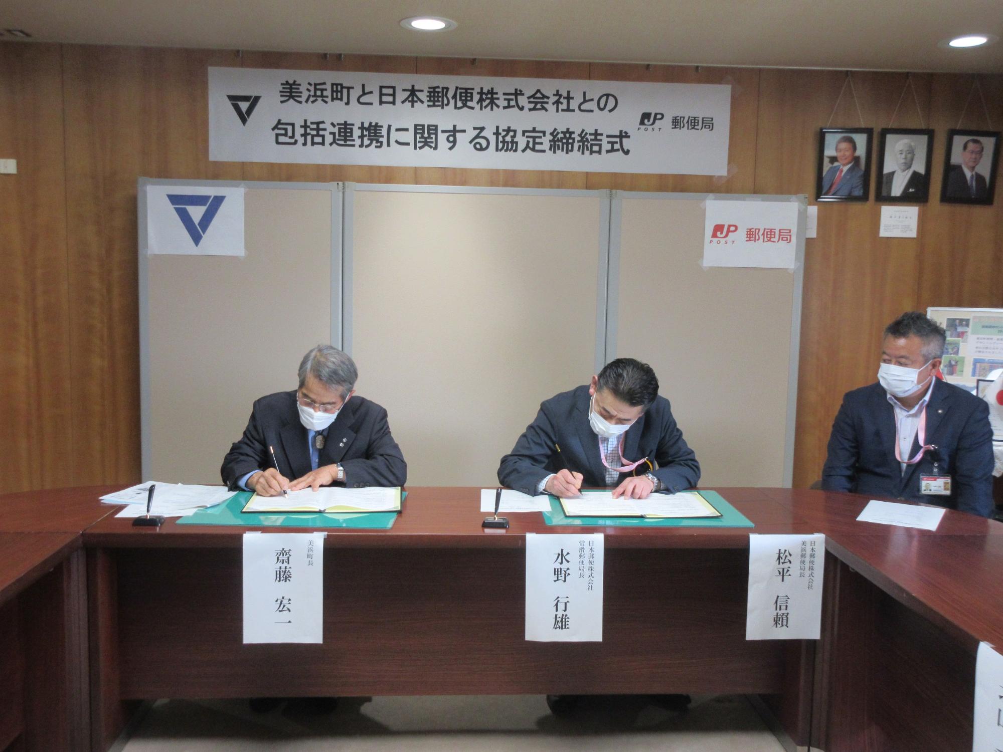 町長 齋藤宏一氏と常滑郵便局長 水野行雄氏が協定書にサインしている写真