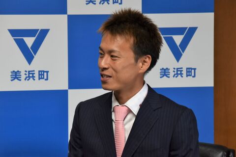 美浜町のバックボードの前で、笑顔を見せる磯部選手の横顔をアップで撮影した写真