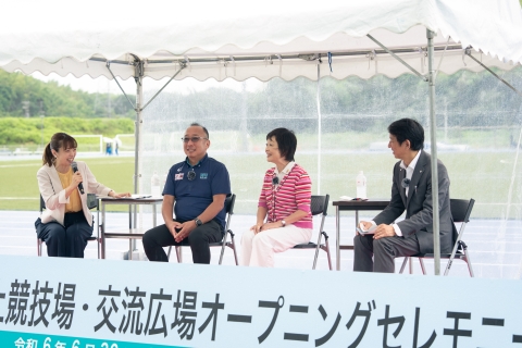 白いテントの下、左の女性がマイクを持ち話をし、増田明美さんや関係者が椅子に座っているオープニングイベントのトークショーの様子の写真