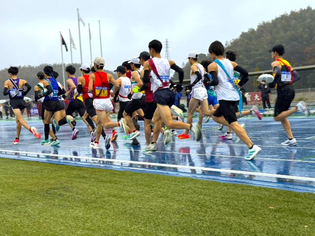 東海学生駅伝対抗選手権大会で選手たちが陸上競技場のトラックを走っている後ろ姿