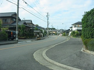 緩やかな曲線を描く登り坂の道路の両側に住宅が並んでいる新しい町を写した写真