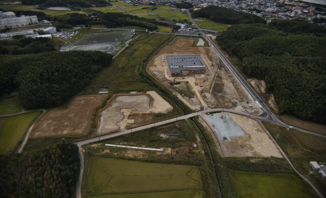 周囲に民家や鬱蒼と茂った森が点在する建設予定地で調整池の設置工事が進められている様子を令和3年(2021)年10月斜め上空から撮影した写真