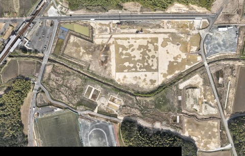 周囲を鬱蒼と茂った森が点在する建設予定地で、観覧スタンドの基盤設備工事が行われている様子を令和4(2022)年3月上空から撮影した写真