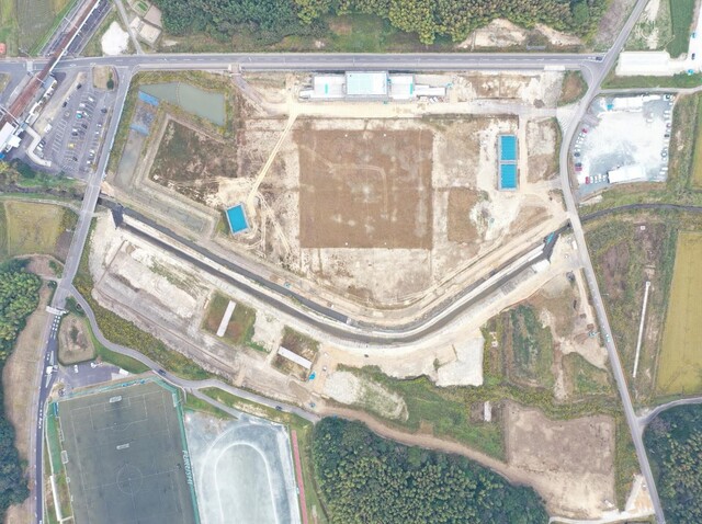 周囲を鬱蒼と茂った森が点在する建設予定地で工事が行われている様子を令和4年(2022)年10月上空から撮影した写真