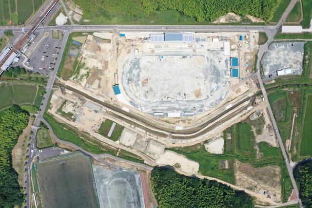 周囲を鬱蒼と茂った森が点在する建設予定地で工事が行われている様子を令和5年(2023)年6月上空から撮影した写真