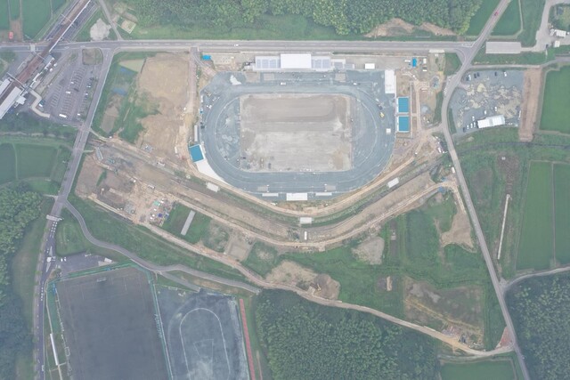 周囲を鬱蒼と茂った森が点在する建設予定地で工事が行われている様子を令和5年(2023)年7月上空から撮影した写真