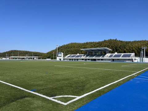 観覧スタンドが向かって右側に見え、サッカーコートのコーナー部分から陸上競技場全体を撮影した写真