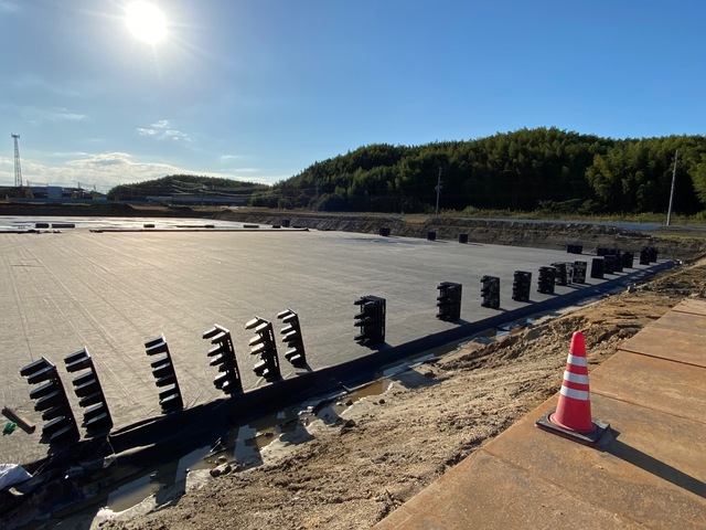 陸上競技場予定地の周囲に黒色のプラスチック製の資材が搬入され横に並んでいる、調整池の設置工事中の様子の写真