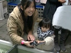 小さな子供が女の子と一緒にウミガメの赤ちゃんを持ち上げ笑顔でカメラを見ている写真