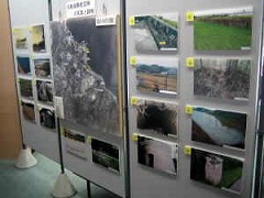 パーテーションに航空写真や様々な場所を撮った写真が並べて展示されている写真