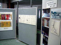 屋内や屋外などを撮った写真や文書の様な資料が並べて展示されている写真