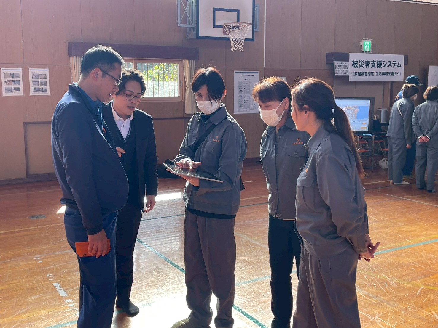 タブレットを操作しシステムの入力をする美浜町職員と、それを見学する4名の美浜町職員