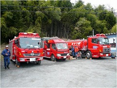 消防車2台と水の補給を行う水槽車が空き地に並んでいる写真