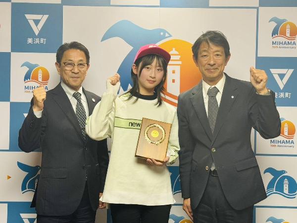 表敬訪問した中野綸子さん、町長、教育長がガッツポーズしている様子