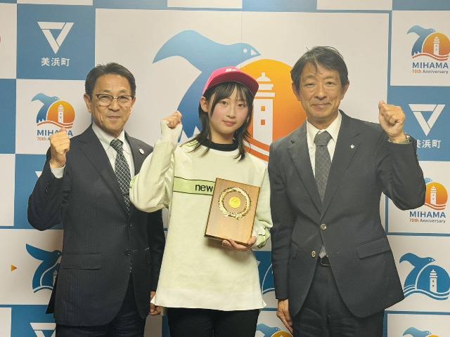 表敬訪問した中野綸子さん、町長、教育長がガッツポーズしている様子