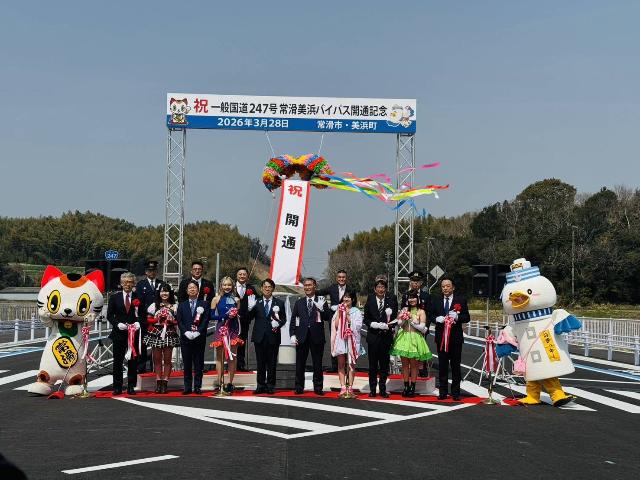 一般国道247号線常滑美浜バイパス開通記念のパネルの下にあるくす玉を割り、伊藤衆議院議員、大村愛知県知事をはじめとする来賓と写真を撮っている様子