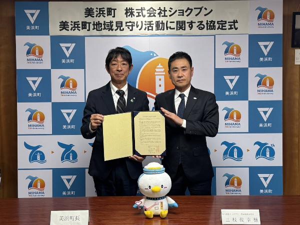 株式会社ショクブン様と地域見守り活動に関する協定書を締結した際、町長と代表が協定書を持ち並んで写真を撮っている様子