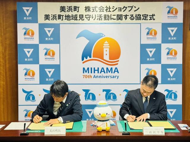 株式会社ショクブン様と地域見守り活動に関する協定書を締結した際、町長と代表が協定書に署名している様子