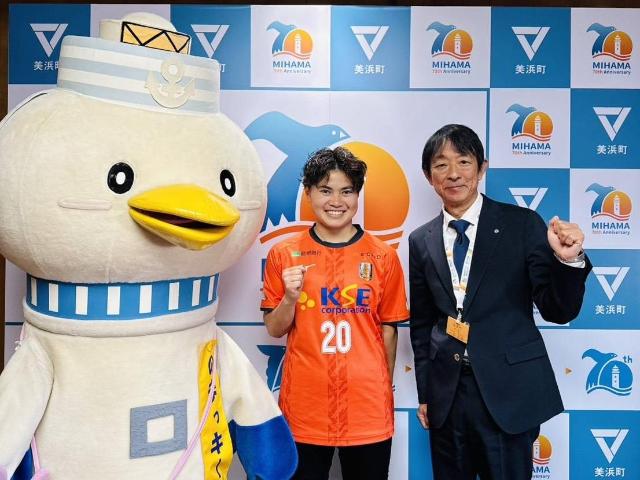 表敬訪問したガッツポーズする都筑かんなさんと町長、のまっキーが一緒に写っている様子。