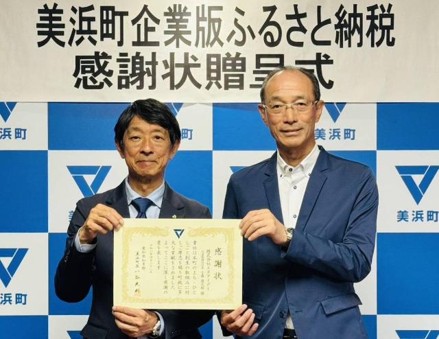 株式会社エヌアイデイの代表者と町長が感謝状をもっている様子。