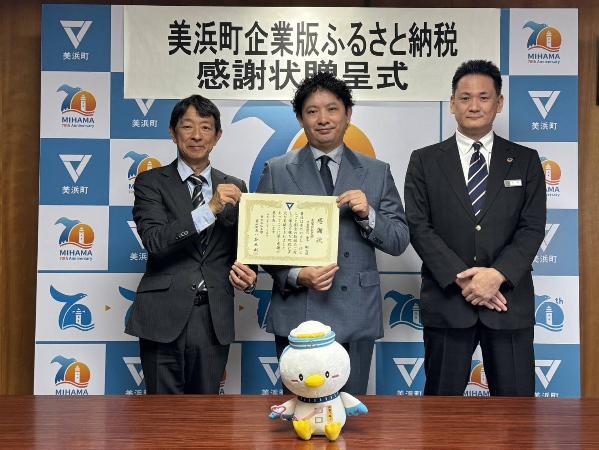 町長と有限会社名栄代表者が寄附感謝状を持ち、仲介者である名古屋銀行代表者と一緒に写っている様子