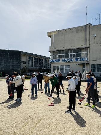 奥田小学校にて開催されたスナッグゴルフ教室で、児童がプロにクラブの握り方や振り方を教わっている様子。