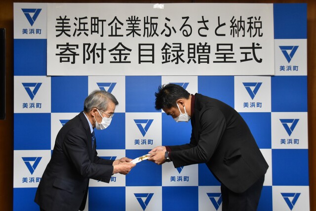 スーツを着た男性が寄付金を渡している写真