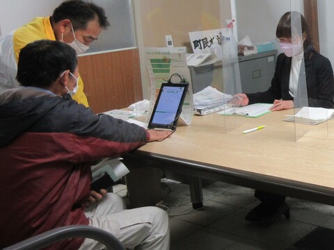 男性が手のひらをセンサーの上に置き画面を見ながらベジチェック体験をしている写真