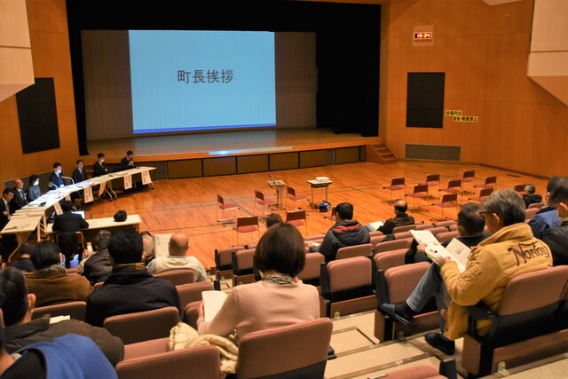 舞台に大きなスクリーンが設置された大きなホールで、令和5年度第2回町政報告会が開催されている様子を写した写真