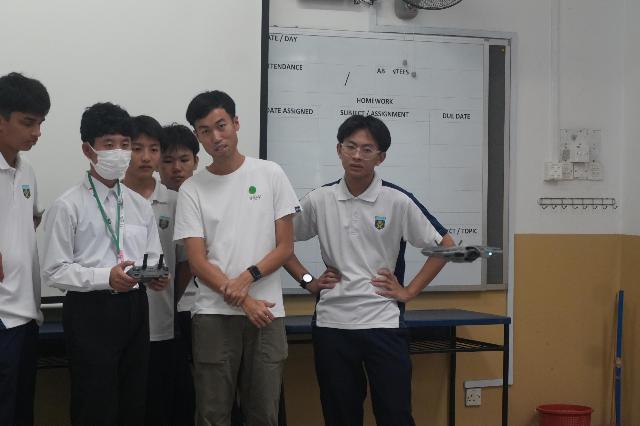 ニーアン中学校での授業で、派遣された生徒がドローンを操縦し、ニーアン中学校の生徒と先生が見守っている様子。