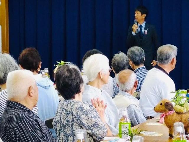 北方区の敬老会で、町長が参加者の前であいさつしている様子。