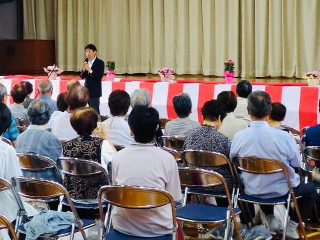 河和区の敬老会で、町長が壇上で参加者に話している様子。