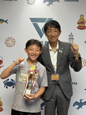 トロフィーを持ってガッツポーズする中野晃成さんと町長の様子