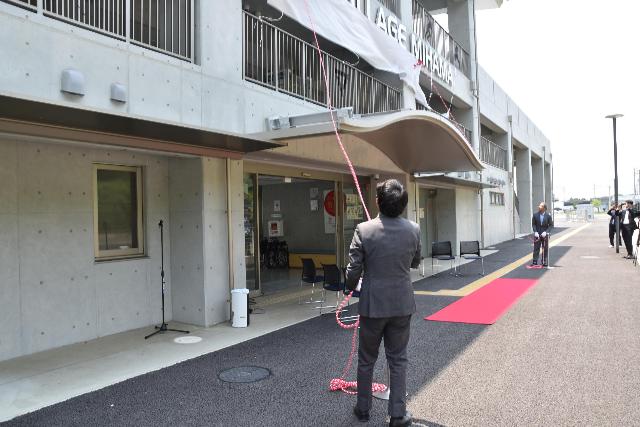 美浜町運動公園陸上競技場で行われたネーミングライツの除幕式で幕を引っ張る様子