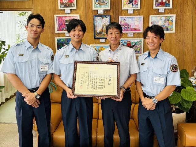 中川隊員と町長が賞状を持ち、近藤隊員、坂本隊員と一緒に写っている様子