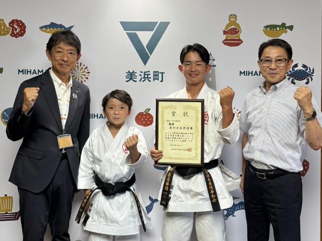 賞状を持ちガッツポーズをする茶谷泰遥さん、ガッツポーズをする廣田睦空さんと町長、教育長が写っている様子。