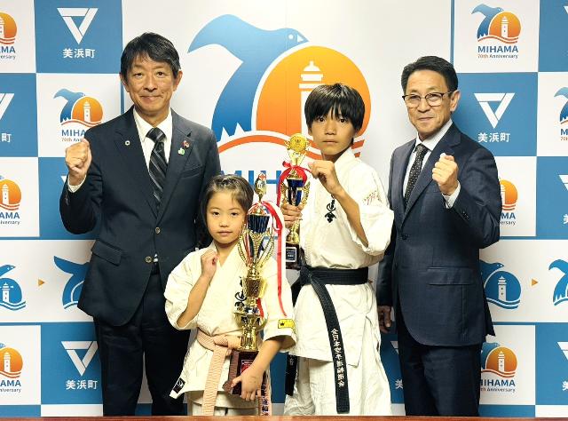 空手の全国大会への出場を決めた森下さんと橋本さんが表敬訪問し、町長と教育長と並んで写真を撮っている様子