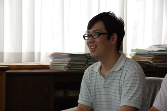 メガネをかけ水色のストライプの半そでシャツを着ている石田祐康さんを横から写した写真