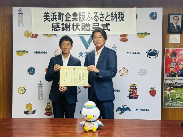 幸栄電気株式会社様と町長が感謝状を一緒に持っている様子