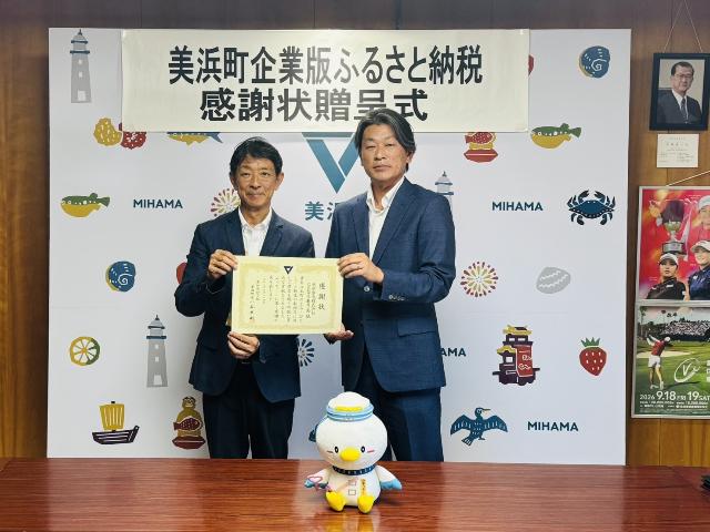 幸栄電気株式会社様と町長が感謝状を一緒に持っている様子
