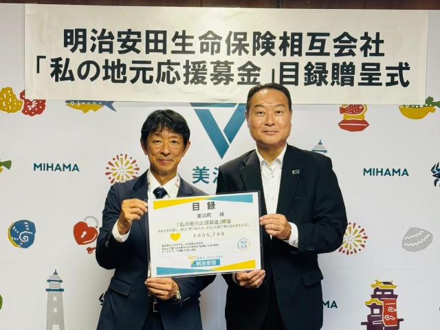 町長と明治安田生命相互保険会社の代表者が、目録をもっている様子。
