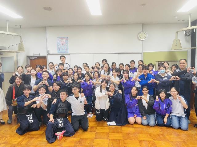 ニーアン中学校の生徒が野間中学校に来校した時の写真で両校の生徒が肩を組んだり手でハートをつくっている様子