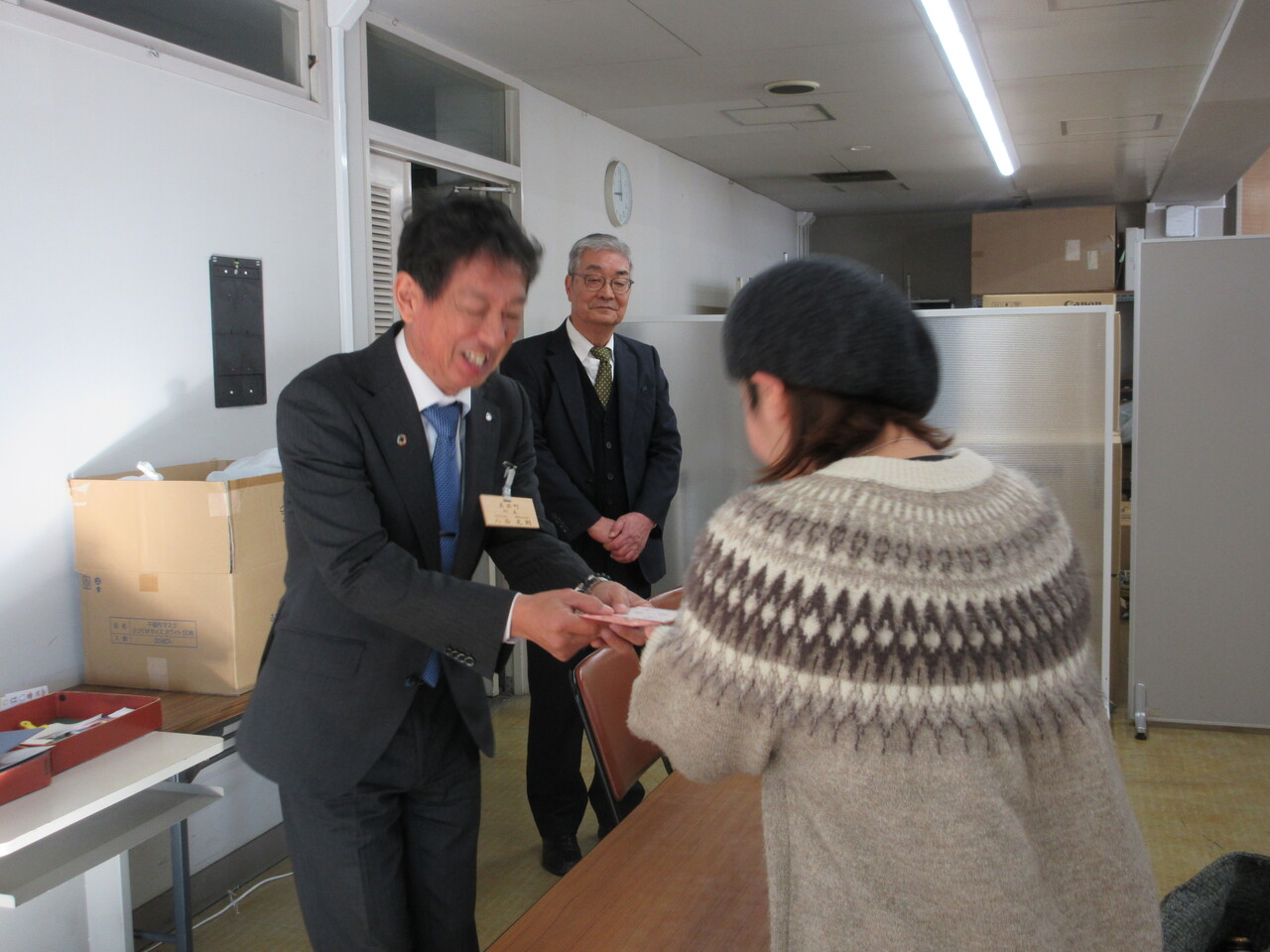 長机が設置されている室内で、町長が福祉お年玉を笑顔で女性に手渡ししている写真