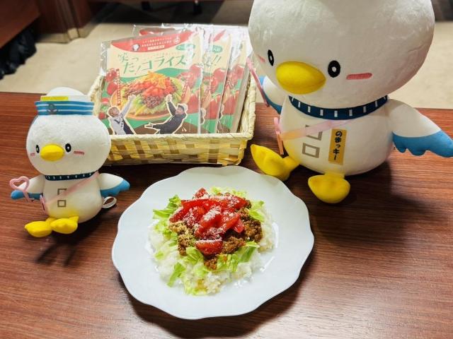 笑った！コライスの調理見本とのまっキーのぬいぐるみが並んでいる様子。