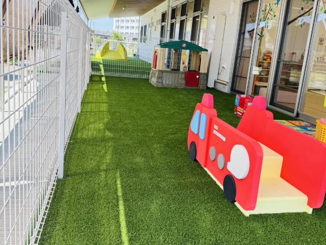 みはまーれの幼児園庭に、寄付いただいた消防車遊具がその他の遊具と一緒に設置されている画像