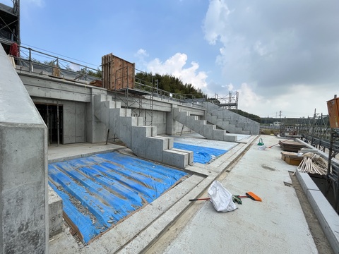 陸上競技場観覧スタンド2階部分の床がビニールシートで覆われ、通路部分に箒と塵取りが置かれている写真