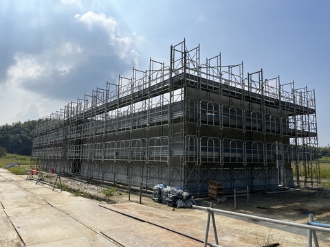 陸上競技場器具庫の周囲に足場が設置され、壁を設置している工事の様子写真