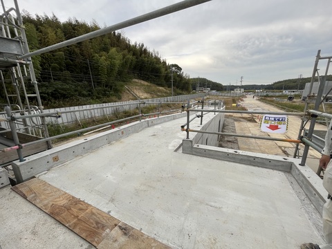 周囲に足場が設置され、奥まで続く緩やかに降るスロープ部分で型枠解体工事を行っている様子の写真
