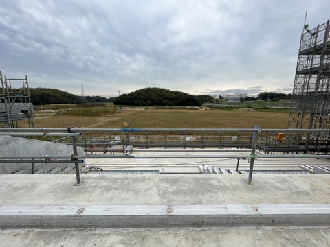 型枠解体工事が行われた陸上競技場観覧スタンド3階部分から木々が鬱蒼と茂った森や鉄塔が立っている周囲を撮影した写真